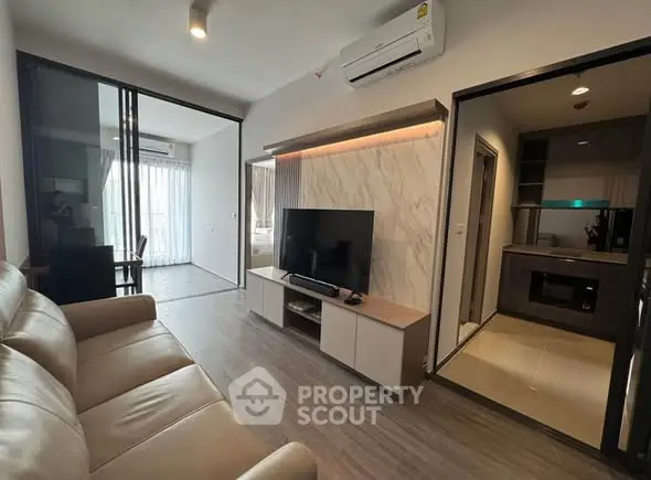 Modern living room with sleek design, featuring a TV and air conditioning, adjacent to a stylish kitchen.