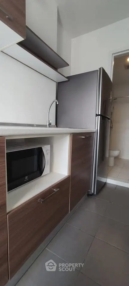 Modern kitchen with sleek cabinetry and stainless steel fridge in a compact layout.