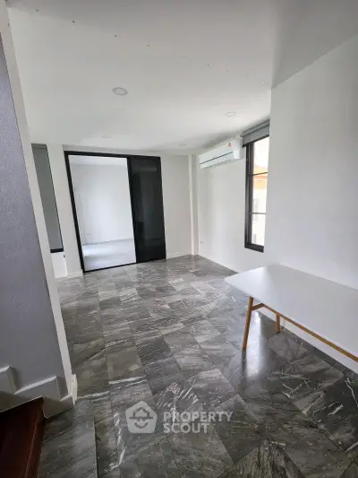 Spacious modern living area with sleek tile flooring and large windows for natural light.