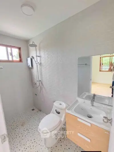 Modern bathroom with shower, toilet, and vanity in bright natural light.