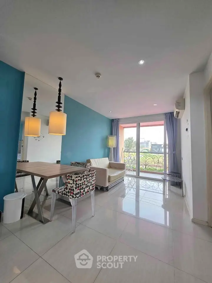 Modern living room with blue accent wall, stylish lighting, and large windows offering natural light.