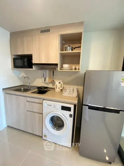 Modern kitchen with washing machine, microwave, and fridge in compact layout