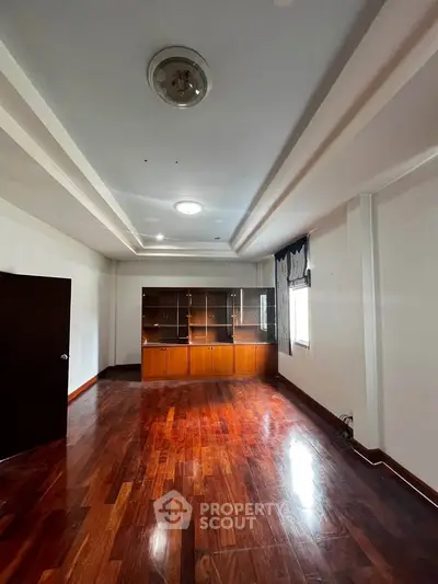 Spacious living room with wooden flooring and built-in shelves, perfect for modern living.