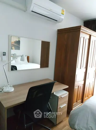 Cozy bedroom with wooden wardrobe, desk, and air conditioning unit, perfect for comfortable living.