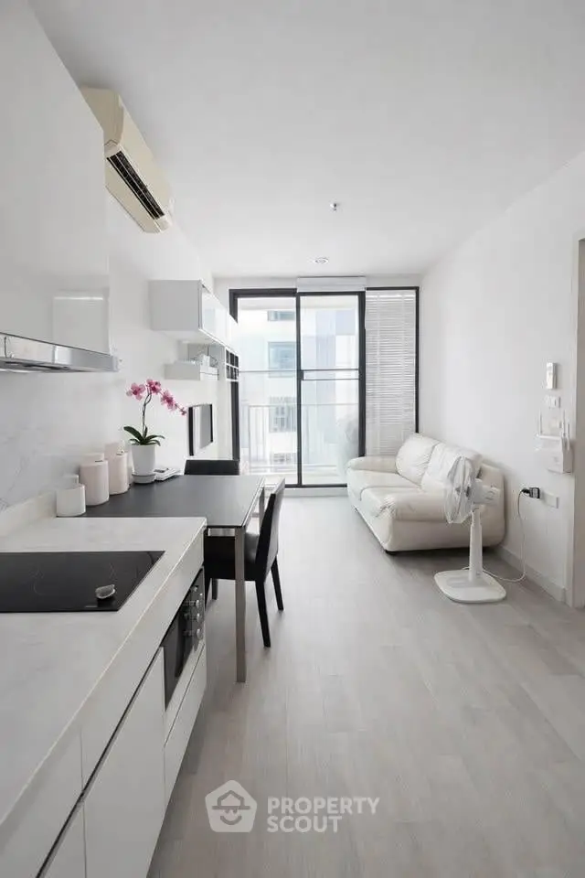 Modern minimalist kitchen and living room with sleek white design and natural light.