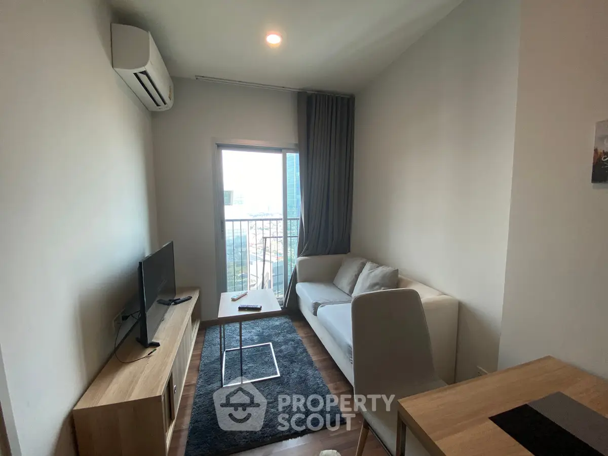 Modern living room with balcony view, featuring sleek furniture and natural light.