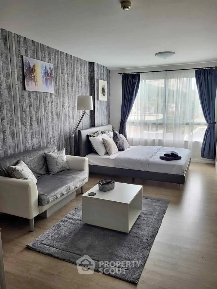 Modern bedroom with stylish decor and natural light, featuring a cozy seating area.
