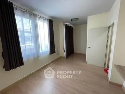 Spacious empty room with large windows and wooden flooring