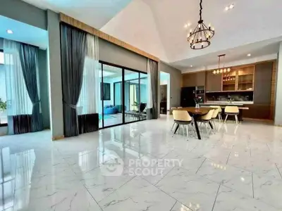 Spacious modern living room with open kitchen and elegant dining area, featuring high ceilings and stylish lighting.