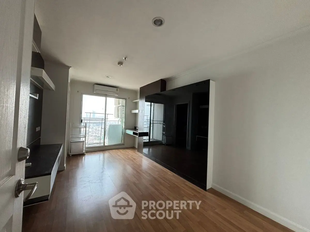 Spacious modern living room with wooden flooring and large windows for natural light.