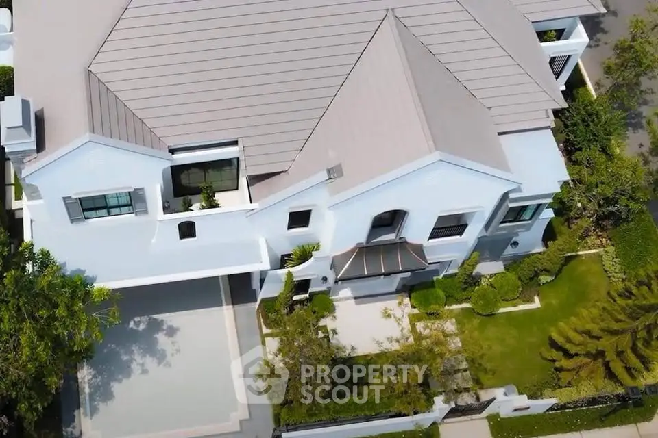Stunning aerial view of a modern luxury home with landscaped garden and spacious driveway.