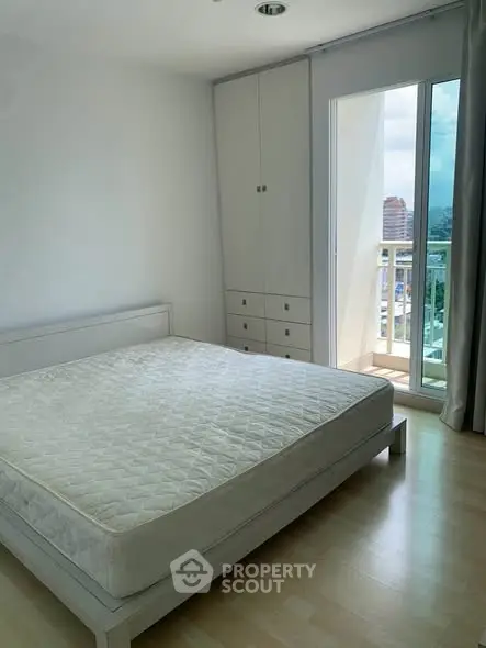 Bright bedroom with large window and balcony access, featuring a minimalist design and ample natural light.
