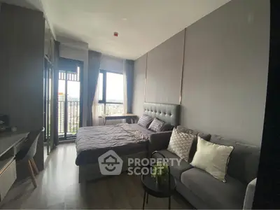 Modern studio apartment with cozy bed and stylish sofa, featuring a small balcony with city view.