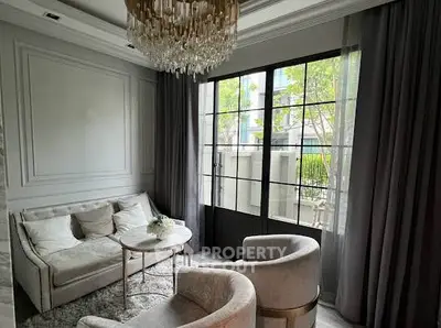 Elegant living room with plush seating and chandelier, featuring large windows and stylish decor.