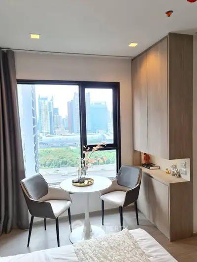 Modern bedroom with city view, featuring cozy seating area and elegant decor.
