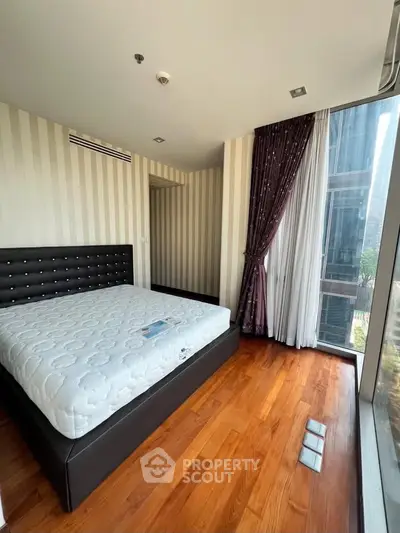 Luxurious bedroom with floor-to-ceiling windows and elegant hardwood flooring in a modern high-rise apartment.