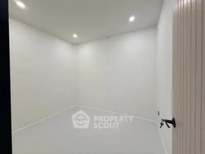 Minimalist empty room with white walls and ceiling lights, ideal for customization.