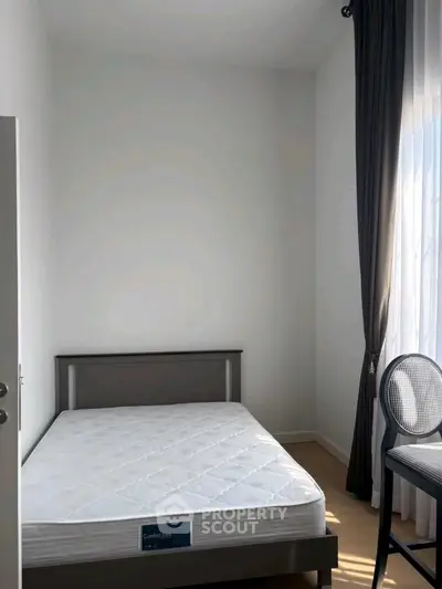 Cozy minimalist bedroom with natural light and modern furnishings.