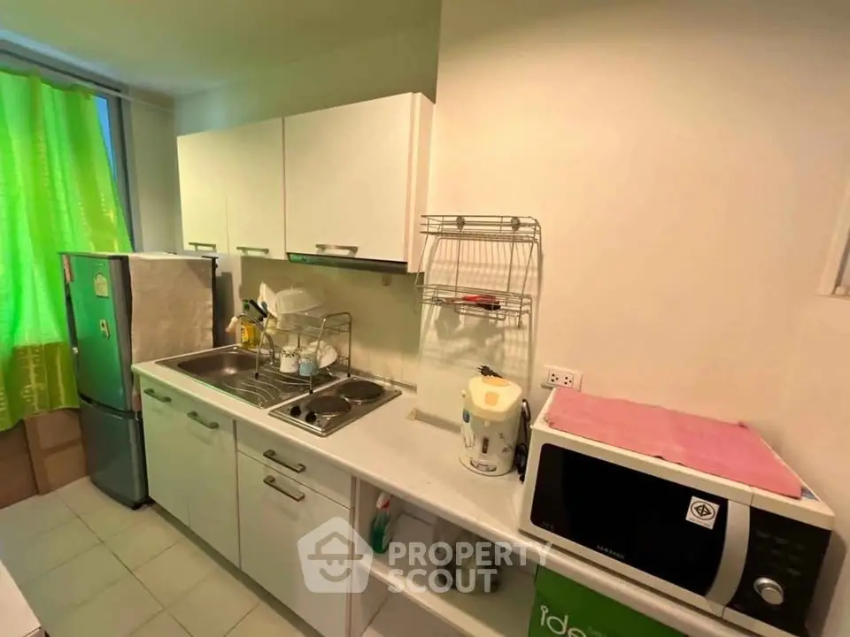 Modern kitchen with sleek white cabinets, stainless steel sink, and essential appliances for convenient cooking.