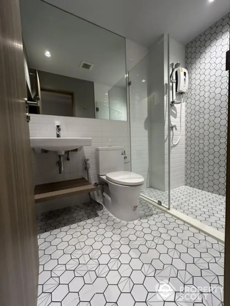 Modern bathroom with geometric tile flooring and glass shower enclosure