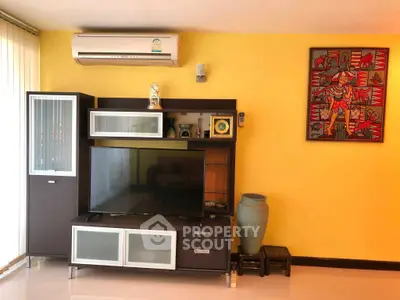 Stylish living room with modern entertainment unit and vibrant yellow accent wall.