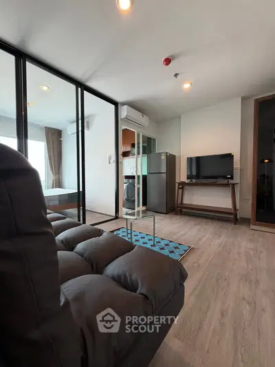 Modern living room with glass partition, sleek furniture, and natural light.