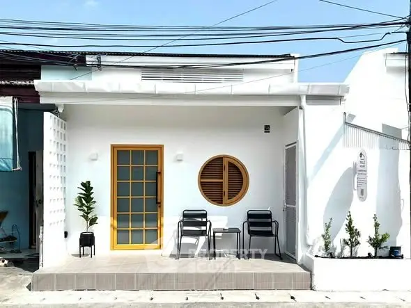 Charming modern white house with unique round window and cozy front patio.