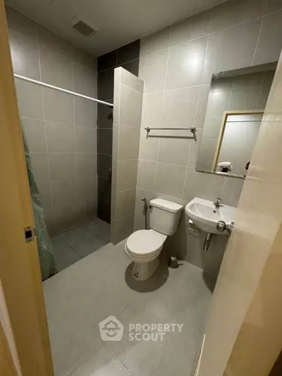Modern bathroom with sleek tiles and compact design, featuring a shower and toilet.