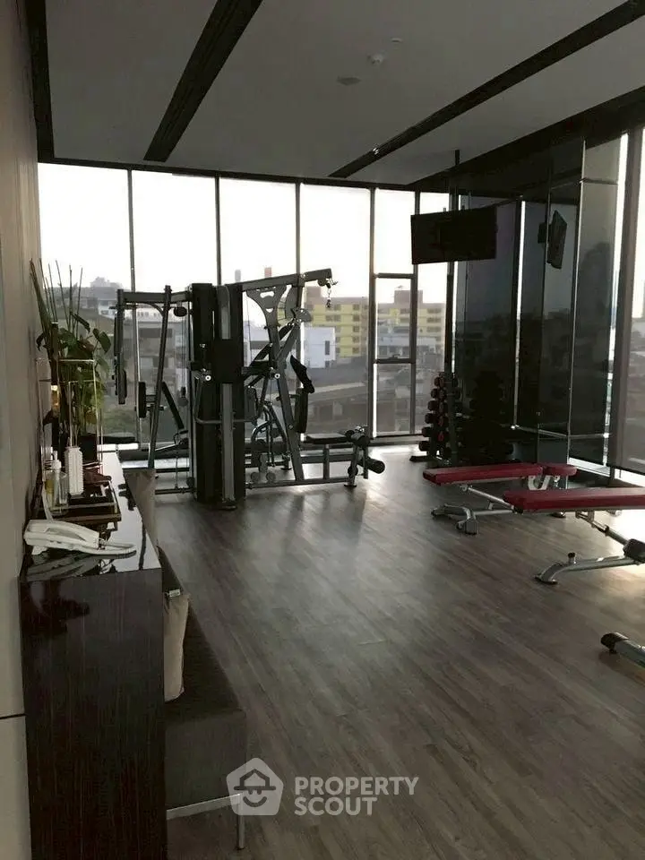 Modern gym with city view and fitness equipment in luxury building.