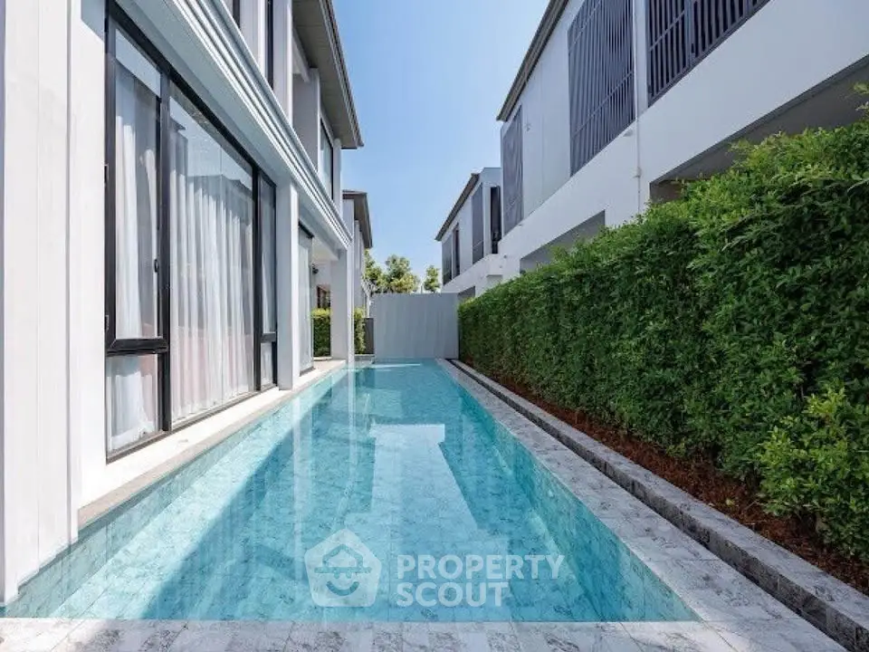 Luxurious modern home with sleek private pool and lush greenery, perfect for relaxation and entertainment.