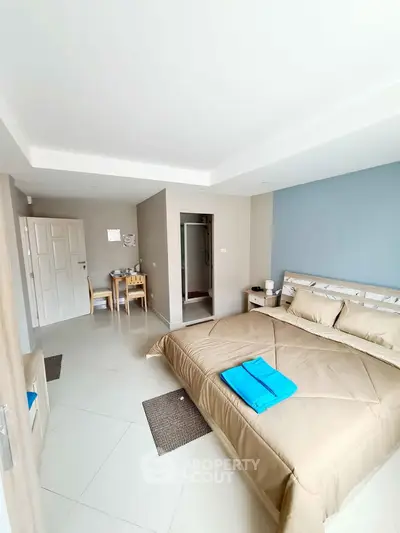 Spacious bedroom with modern decor and ensuite bathroom in a bright apartment.