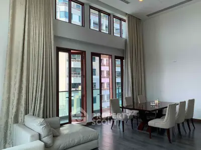 Spacious living room with high ceilings and large windows offering city views, featuring elegant furniture and modern decor.