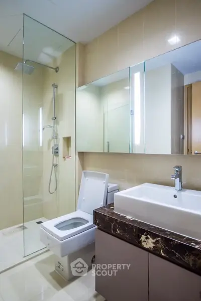 Modern bathroom with glass shower and sleek vanity in luxury apartment.