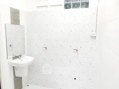 Minimalist white bathroom with wall-mounted sink and tiled walls