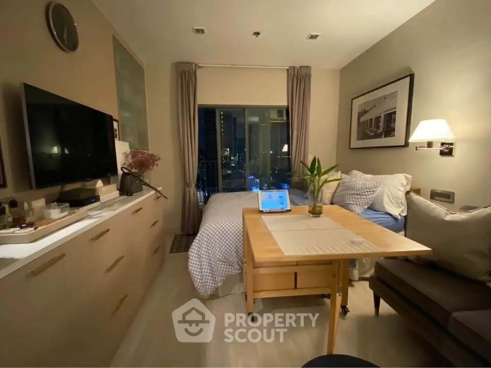 Cozy studio apartment with modern decor and city view, featuring a compact living area and stylish furnishings.