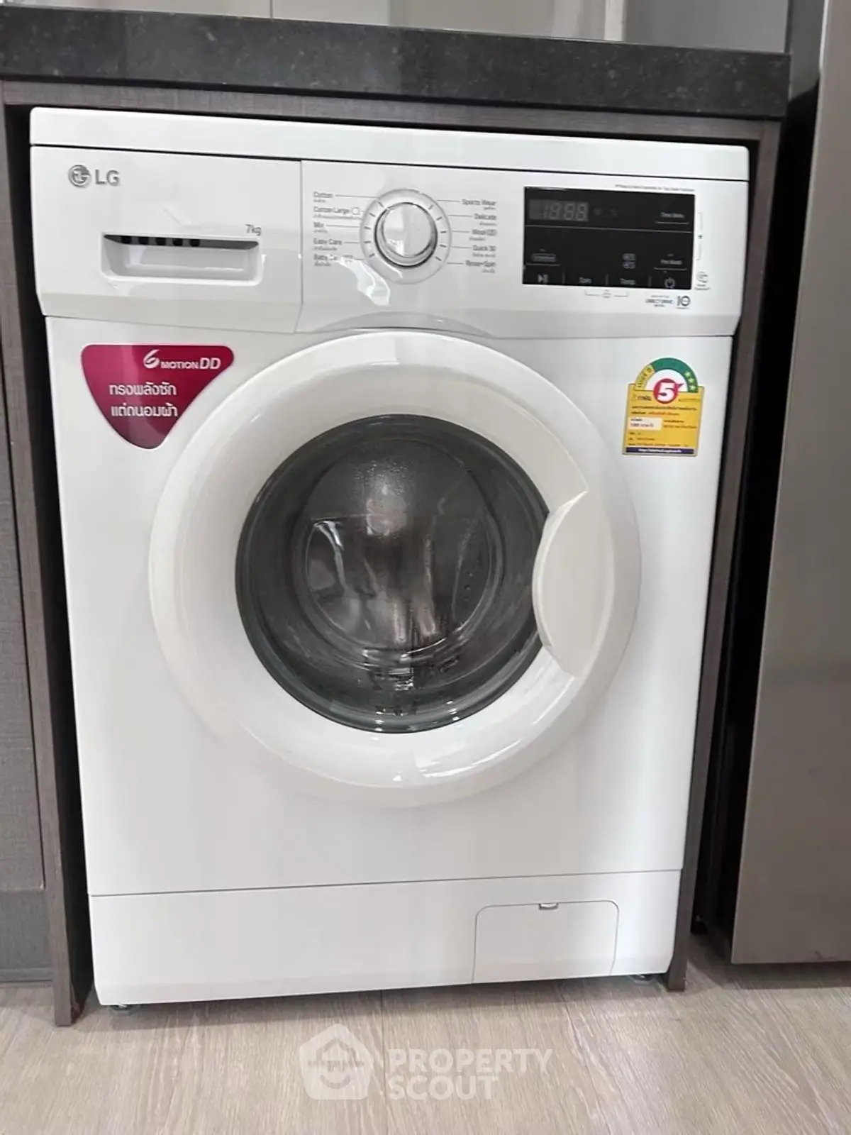 Modern washing machine in sleek laundry area with wood flooring