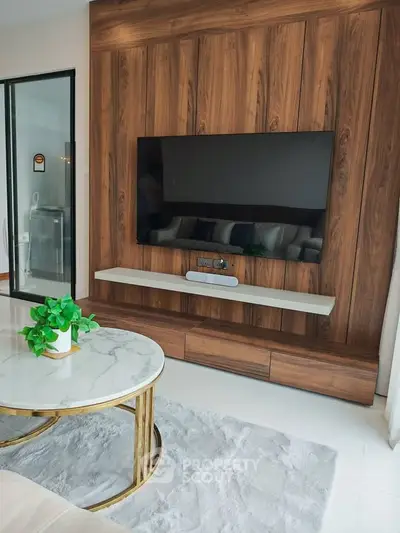 Modern living room with sleek wooden paneling and mounted TV, elegant marble coffee table, and plush rug.
