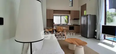 Modern open-plan living room with sleek kitchen and stylish furniture, featuring large windows and natural light.