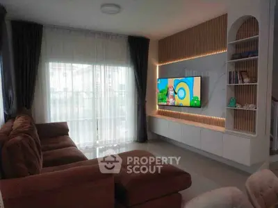 Modern living room with large sofa and wall-mounted TV, featuring elegant curtains and ambient lighting.