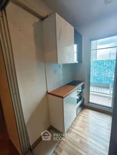 Compact kitchen with modern cabinetry and balcony view