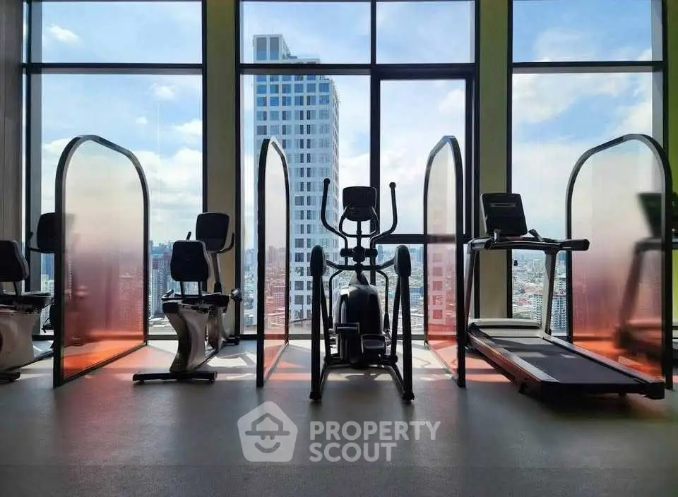 Modern gym with city view featuring exercise bikes and treadmill.