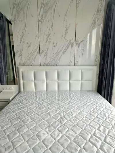 Luxurious bedroom with elegant marble accent wall and plush white headboard