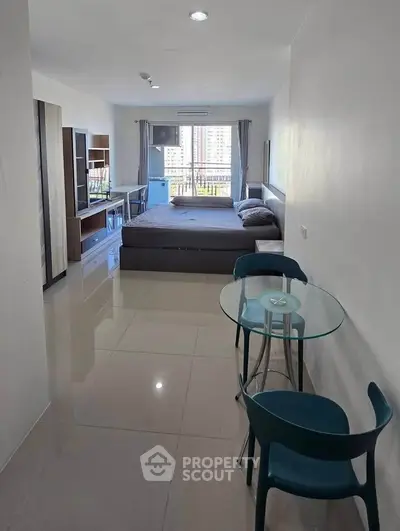 Modern studio apartment with sleek furnishings and city view, featuring a cozy bed and stylish dining area.