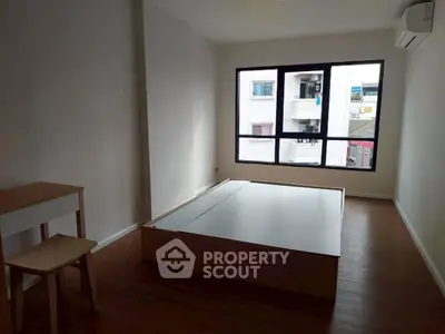 Spacious bedroom with large window and minimalist furniture in modern apartment.
