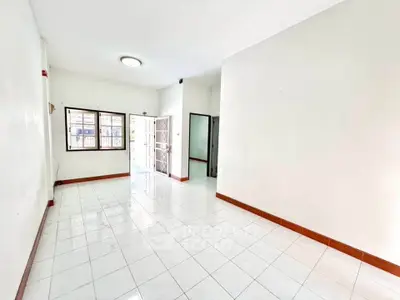 Spacious and bright living room with tiled flooring and large windows.