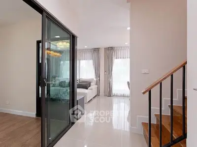 Modern interior with glass sliding doors and elegant staircase in a bright living space.