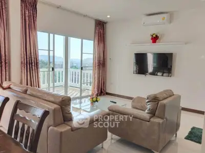 Spacious living room with modern decor and scenic balcony view