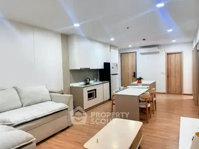 Modern open-plan living room and kitchen with sleek design and cozy furnishings.