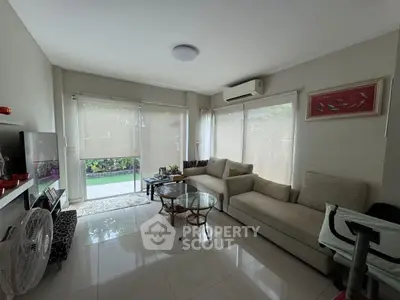 Spacious living room with modern furniture and large windows overlooking garden.