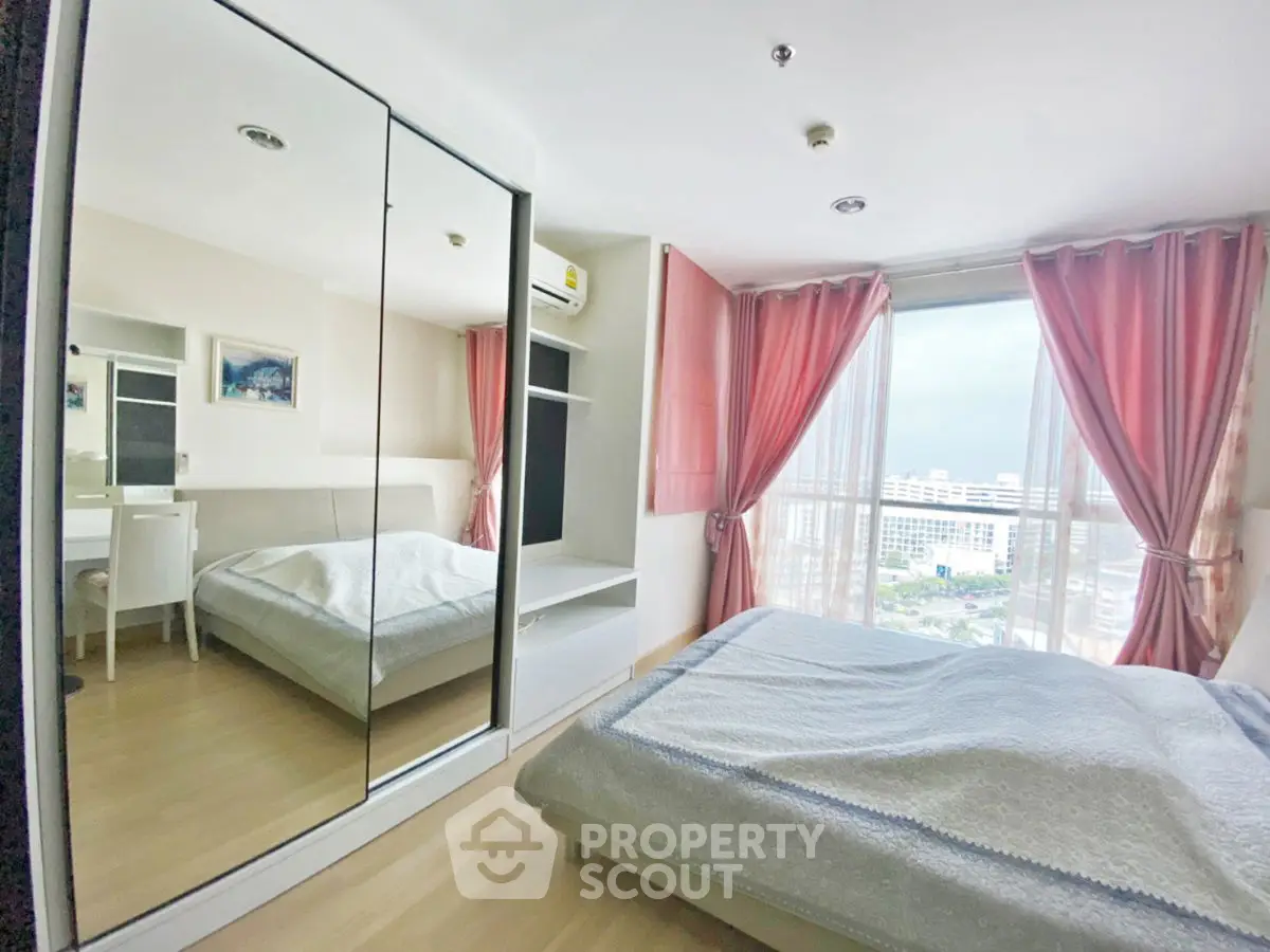 Bright bedroom with mirrored wardrobe and city view from window